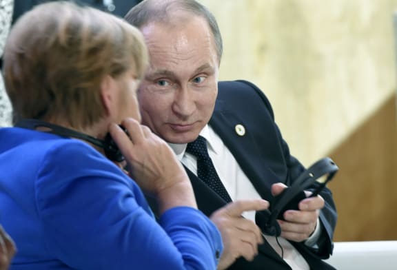 Russian President Vladimir Putin speaks with German Chancellor Angela Merkel during the first day of the COP21 climate change meeting in Paris.