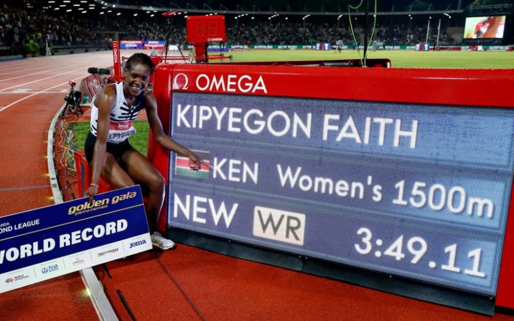 Kenya's Faith Kipyegon poses with the screen as she sets a new world record and wins the women's 1500m final.