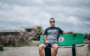 Mark Inman sit on a surfboard bench in memory of his brother tour guide Hayden Marshall-Inman whose body has not been recovered since the Whakaari White Island eruption.