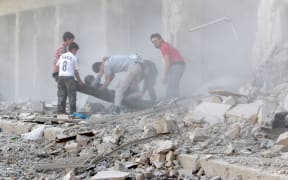 Rescue workers move an injured man from the rubble after airstrike in the Al-Ansari district of Aleppo.