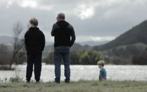 People stand on the banks of a flooded Wairau River on 20 August, 2022.