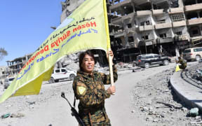 Rojda Felat, a Syrian Democratic Forces (SDF) commander, waves her group's flag at the iconic Al-Naim square in Raqa.