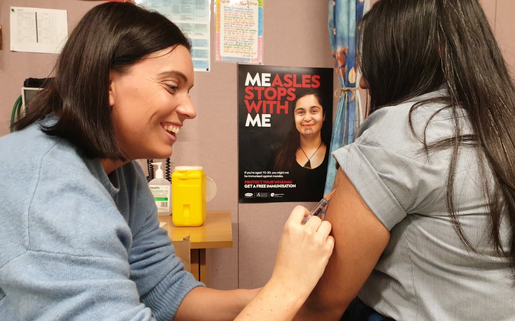 Nurse Laura Williams gives a Māngere College student a measles vaccination.