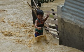 A child wades through floodwaters near his residence at a village in Santa Rosa town, Nueva Ecija province, north of Manila.