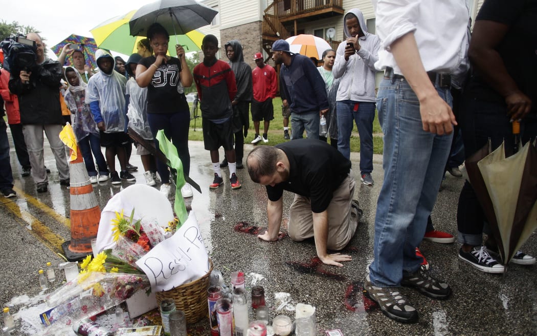 A man kneels and prays at a makeshift memorial where 18-year-old Michael Brown was killed in Ferguson, Missouri.