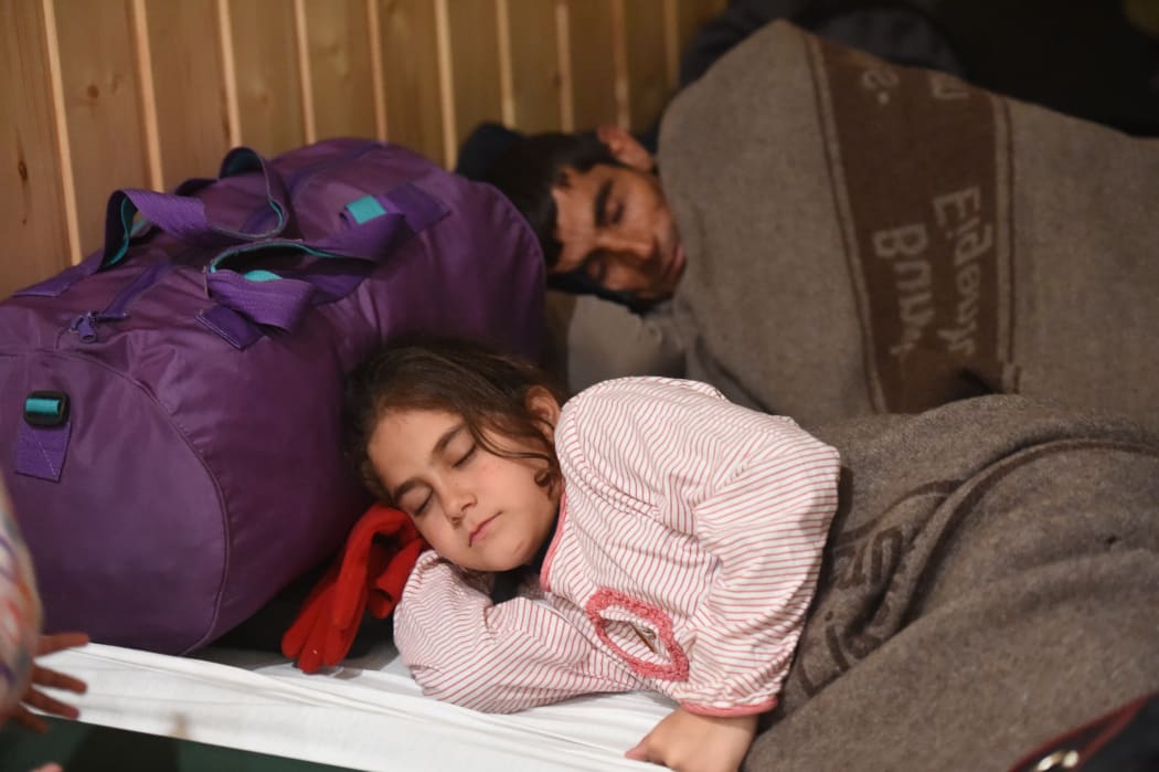 Mohammad from Syria sleeps next to his daughter Aya on a camping bed in refugee accomodation that has been set up in market hall in Kiel, Germany