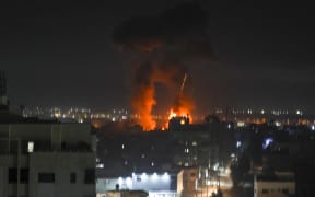 Explosions light up the night sky above buildings in Gaza City as Israeli forces shell the Palestinian enclave, early on 16 June 2021.