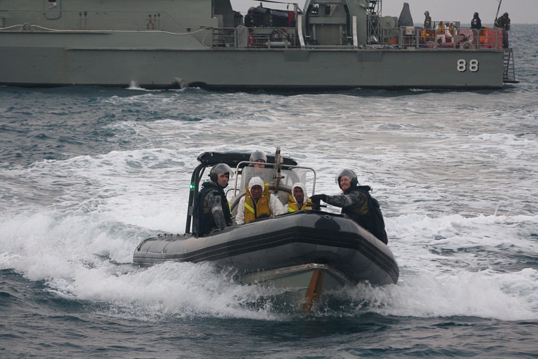 Australian navy personnel transfer Afghanistan asylum-seekers to a Indonesian rescue boat near Panaitan island, West Java on August 31, 2012 after the refugee's boat sunk.