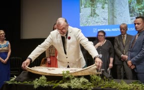 Maui Solomon, Hokotehi Moriori Trust Chair, covers some of the ancestral remains with a cloak of Moriori design at Natural History Museum London Repatriation Ceremony