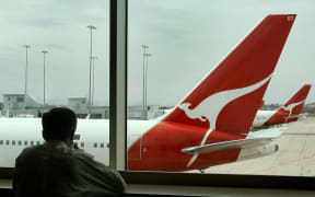 A man looks out over a line of Qantas planes at Melbourne's Tullamarine Airport as the Australian flag carrier and national icon Qantas accepted an increased 11.1-billion-dollar (8.7 billion USD) offer, 14 December 2006, from a private equity group, a day after rejecting a lower bid.