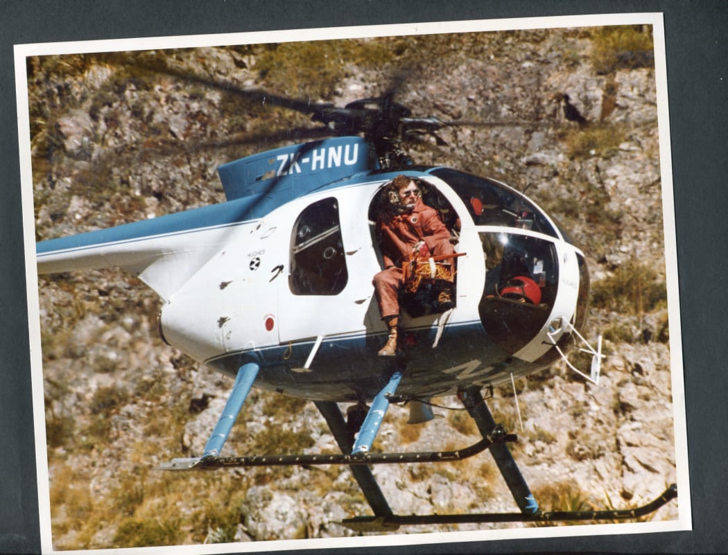 Man sitting outside of door of helicopter