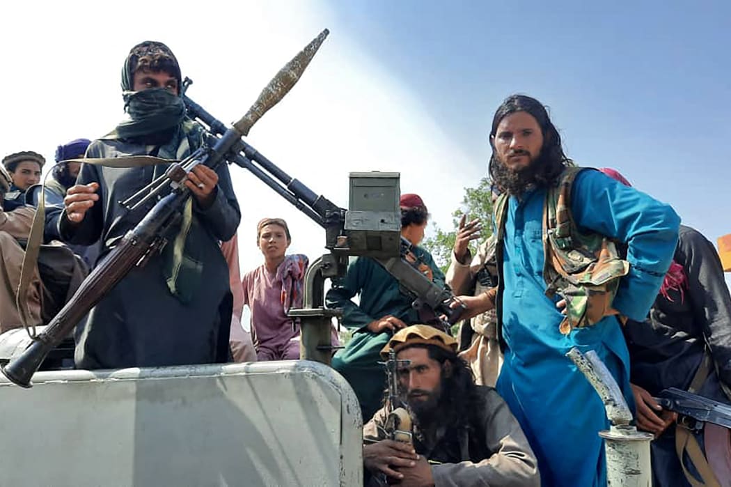 Taliban fighters sit on a vehicle on a street in Laghman province on 15 August 2021.