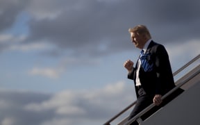 US President Donald Trump gives one of his habitual fist-pumping gestures to a gathered crowd as he exits Air Force One.