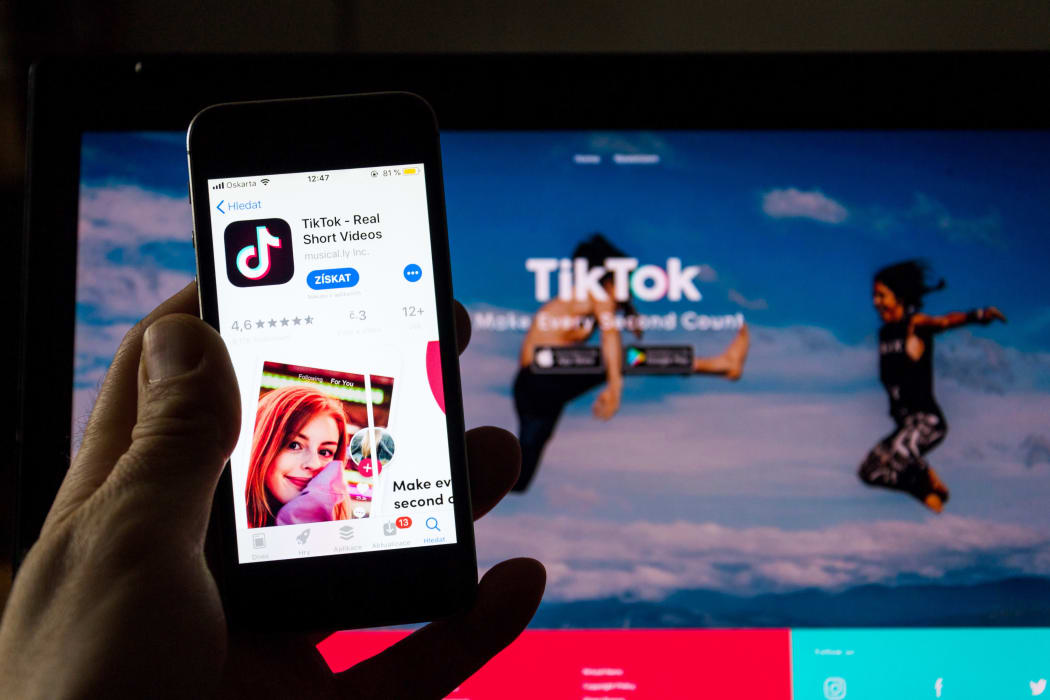 TikTok mobile video-sharing app company logo on phone screen with internet homepage in background.