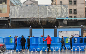 Workers place barriers outside the closed Huanan Seafood wholesale market during a visit by members of the World Health Organization (WHO) team, investigating the origins of the Covid-19 coronavirus, in Wuhan, China's central Hubei province on January 31, 2021.