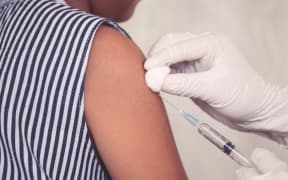 Doctor injecting vaccination in arm of young girl.