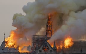 Smoke billows as flames burn through the roof of the Notre Dame de Paris Cathedral