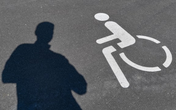 17 June 2020, Brandenburg, Ludwigsfelde: A pictogram for a disabled parking space and a shadow of a person can be seen on the asphalt.