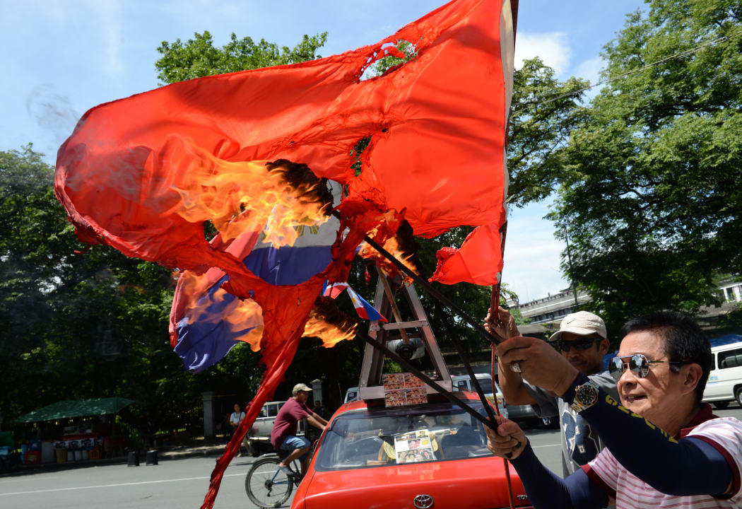 An activist burns a Chinese flag during a protest in Manila against Chinese reclamation of land on disputed South China sea.