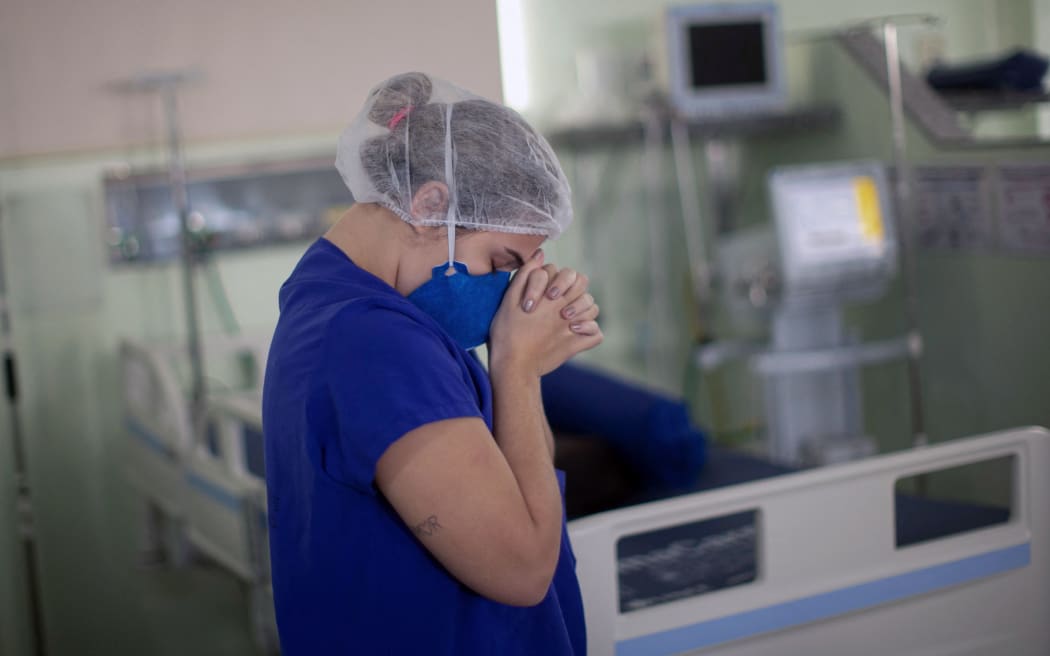 A hospital worker prays as health workers from the Portuguese charity hospital in Belem, Para State, Brazil, sing and pray for colleagues and COVID-19 patients inside the hospital wards and ICU areas as part of Easter celebrations, on April 4, 2021.