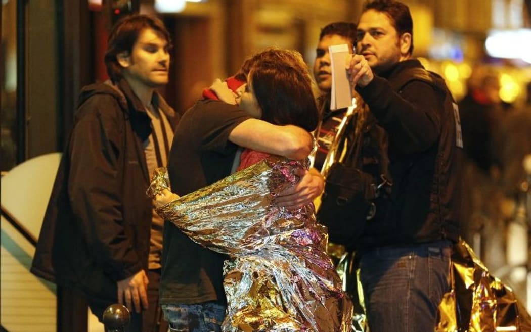 People hug each other before being evacuated by bus, near the Bataclan concert hall in central Paris, on November 14, 2015.