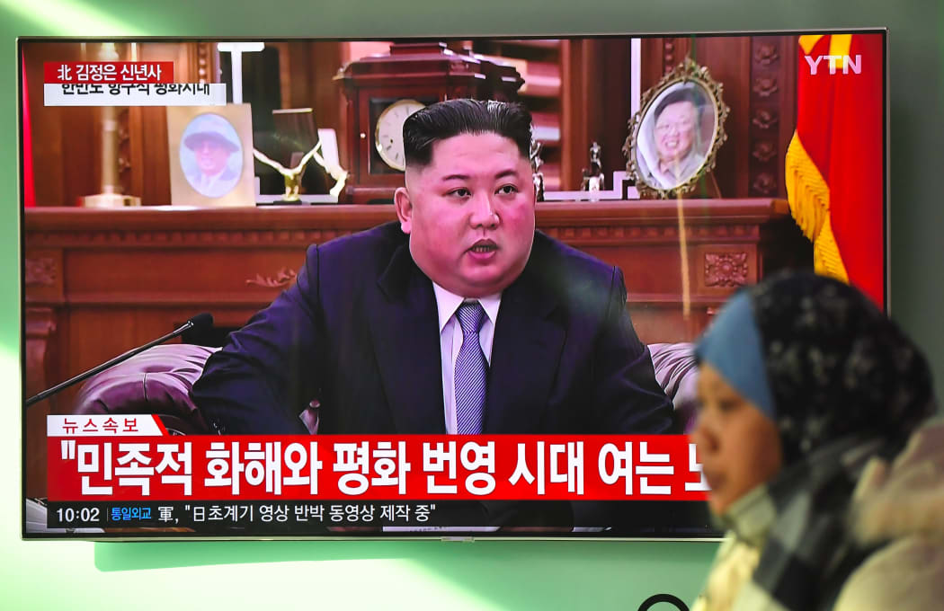 A woman walks past a television news screen showing a New Year speech by North Korean leader Kim Jong Un.