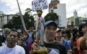A man holds a statuette of Venezuelan popular saint and  a sign that reads "I fight for liberty," as members of the opposition gather to propose amnesty laws for the police and the military, in Caracas, Venezuela