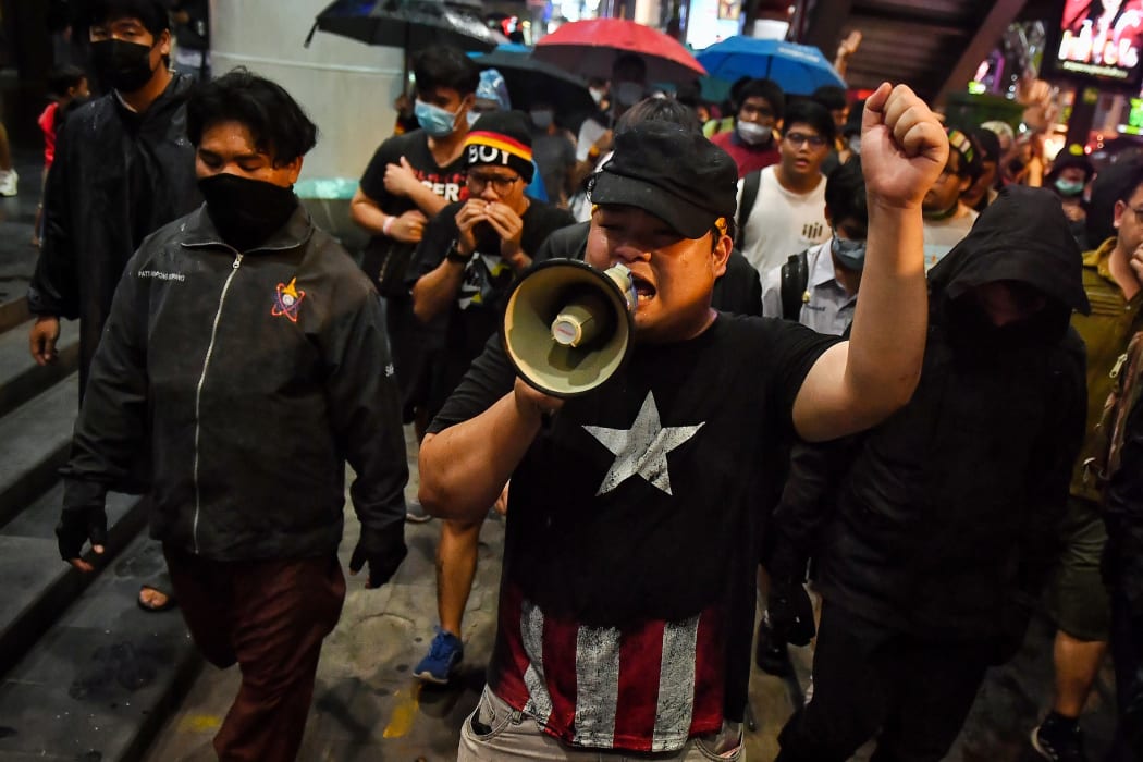 Pro-democracy activist Parit Chiwarak (centre) uses a loudspeaker as he walks with others towards the police headquarters in Bangkok on October 13, 2020.