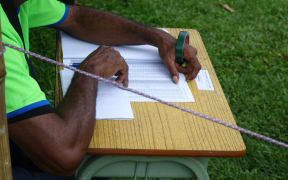A polling officer reads an electoral roll to call out names for voters to step into the polling booth during the Papua New Guinea 2017 election.