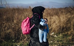 A refugee carries her child after crossing the Greek-Macedonian border near Gevgelija.