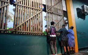 People secure their shop with planks ahead of the arrival of Cyclone Yasa in Fiji's capital city of Suva on December 16, 2020.