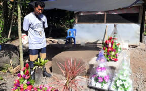 The father Tu'ivale Luamanuvae of Lauli'i Village beside the grave of his three children who died of measles