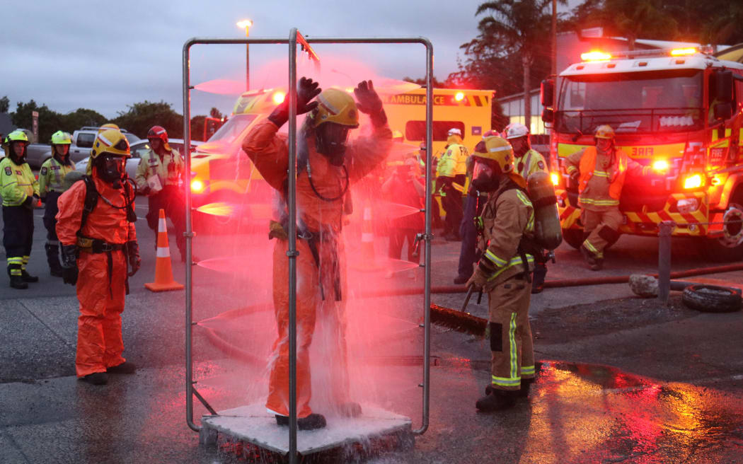 Firefighters take part in a chemical spill exercise in Kerikeri in 2020. A firefighter stands under a makeshift shower to wash off 