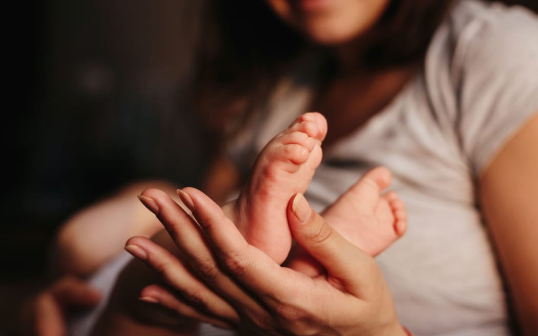 Baby feet in mother hands. Tiny Newborn Baby's feet on female Shaped hands closeup. Mom and her Child. Happy Family concept.