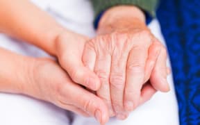 Carer giving helping hands for elderly woman.