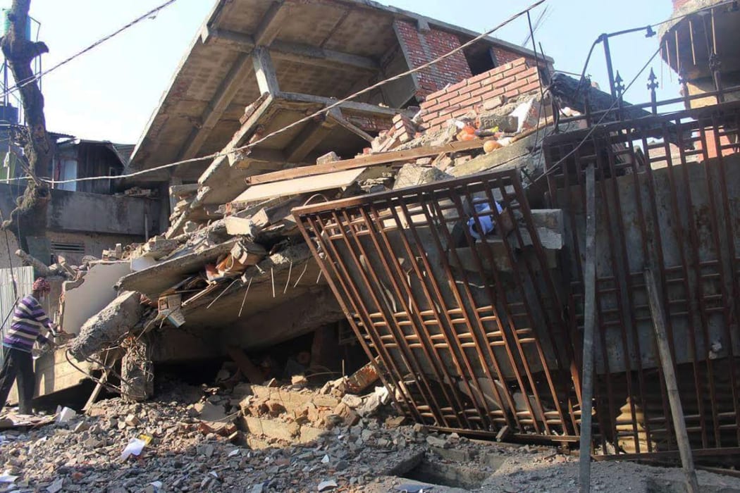 An Indian man stands at a collapsed building following a 6.7 magnitude earthquake, in Imphal