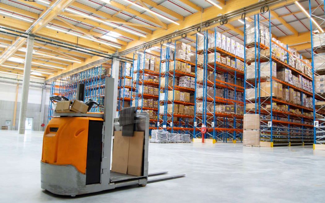 Interior view of a warehouse with racks, pallets, goods, forklifts