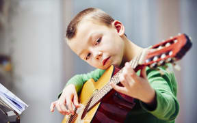 A photo of a little boy playing the guitar at home