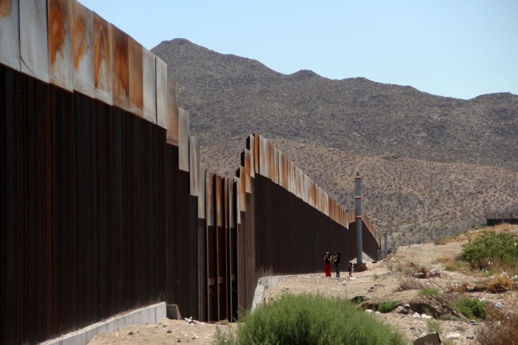 Parts of the US-Mexico border are already sealed off by a wall. A family is pictured standing on the Mexican side of the wall in 2017.
