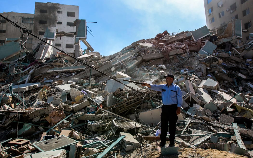 A Palestinian policeman stands in the rubble of a building destroyed by an Israeli airstrike that housed The Associated Press' offices in Gaza City, Palestine on 15 May 2021.