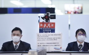 Officers work at a health screening station as they observe passengers arriving on a flight from Wuhan, China, where a SARS-like virus was discovered, at Narita airport, Japan.