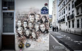 File photo taken on January 7, 2019 shows police officers next to a painting by French street artist and painter Christian Guemy, known as C215, in tribute to members of Charlie Hebdo newspaper who were killed in January 2015.