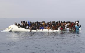 A file photo shows people waiting to be rescued from a sinking dinghy off the Libyan coastal town of Zawiyah, east of the capital, on 20 March, 2017, as they attempted to cross from the Mediterranean to Europe.