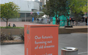 A poem on a box in Aotea Square. It says:Our future's forming out of old dreams: I swear I saw Robbie's eyes gleam.