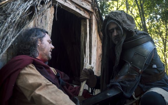 Daniel Carleton as The Bone Farmer sits next to Gene Rugg