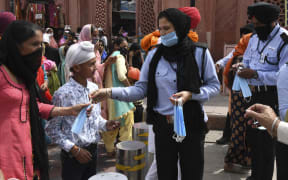 Private security guards distribute facemasks to people during an awareness campaign against the spread of the Covid-19 coronavirus, in Amritsar on 4 April 2021.