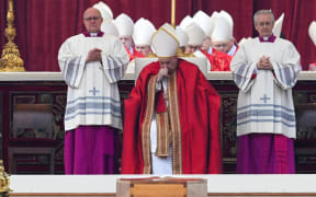 Pope Francis (C) reacts by the coffin of Pope Emeritus Benedict XVI during his funeral mass at St Peter's square.