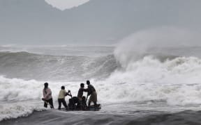 Indian fishermen negotiate their skiff through rough waves ahead of the landfall of Cyclone Hudhud.