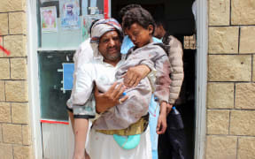 A man transports a child to a hospital after he was wounded in a reported air strike on the rebels' stronghold province of Saada.