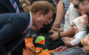 Prince Harry making a silly face at a baby